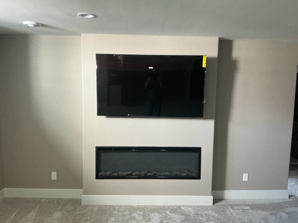 TV mounted above a built-in electric fireplace in a finished basement
